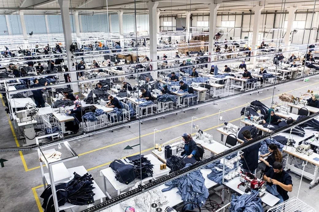 Wide view of garment production lines with sewing stations and fabric bundles